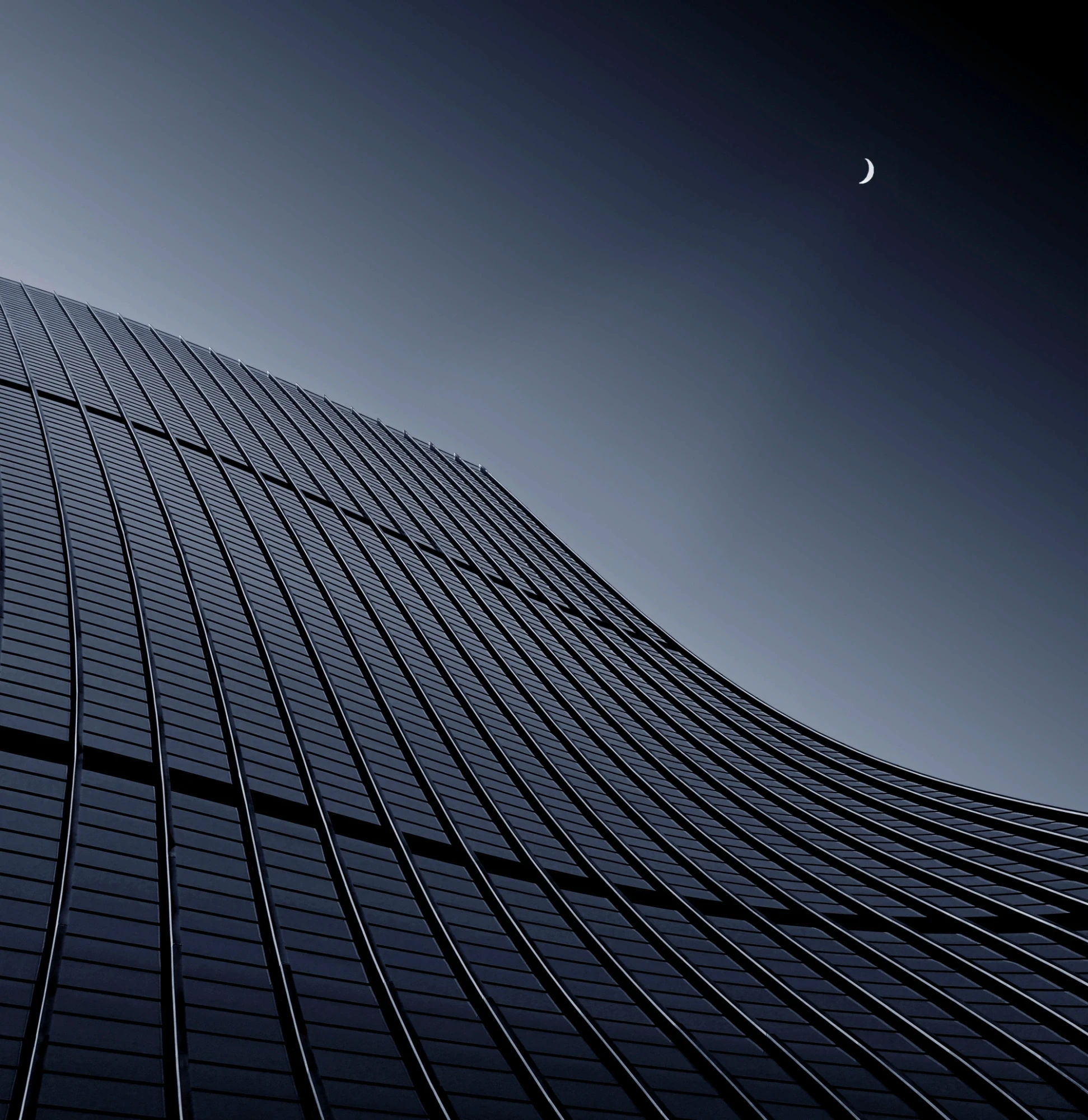 Diagonal steel-and-glass tower facade at dusk